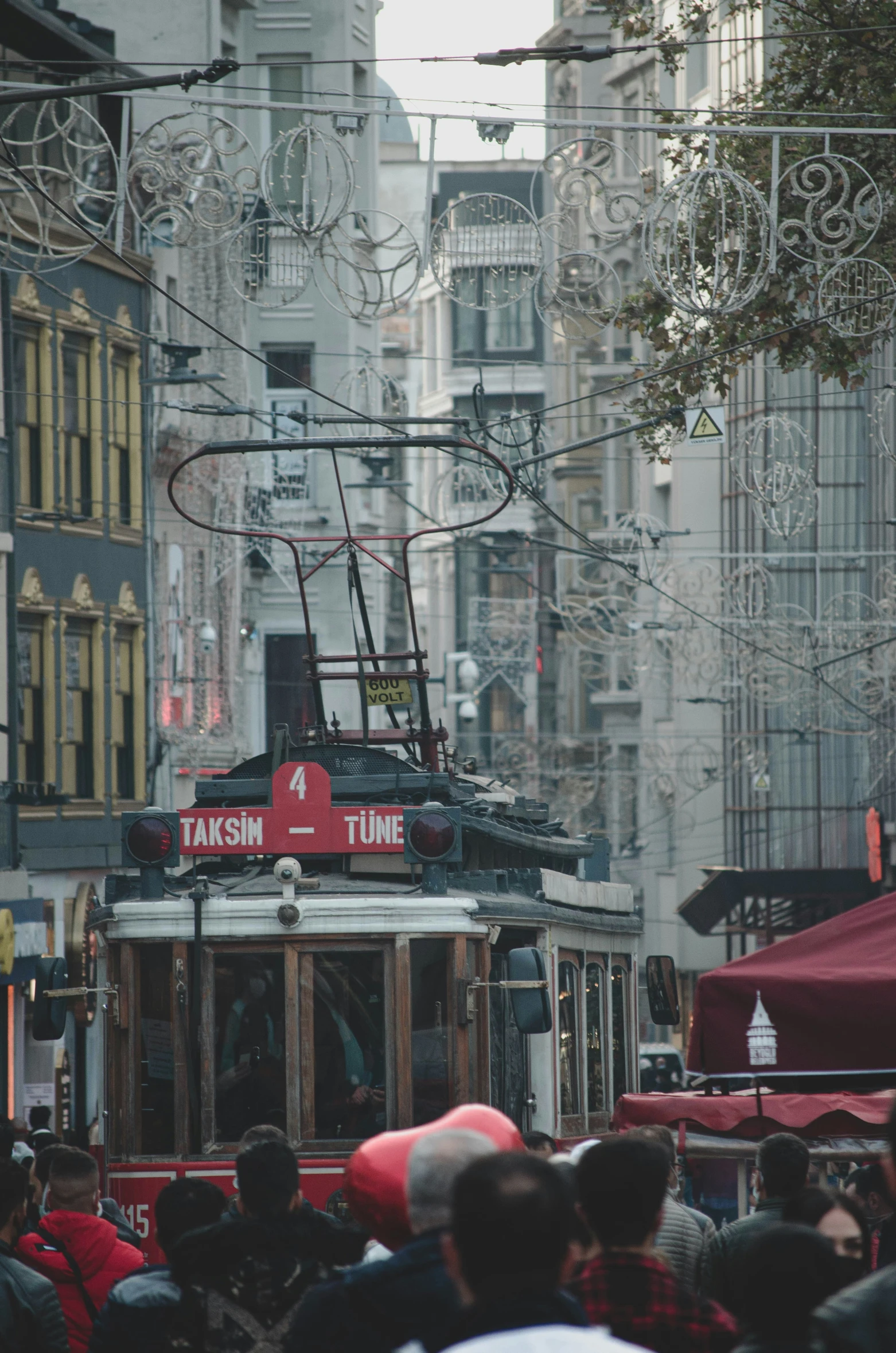 people are standing around a trolley near tall buildings