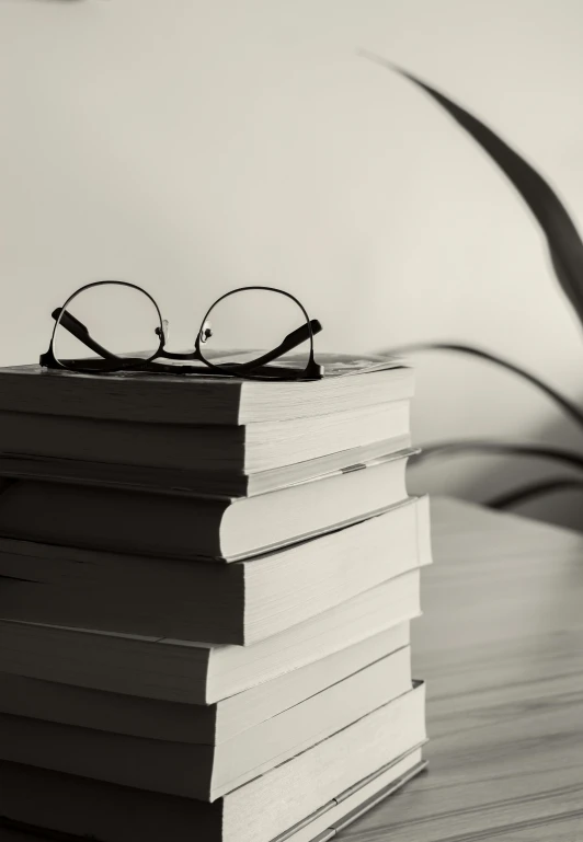 books piled up with eyeglasses on top