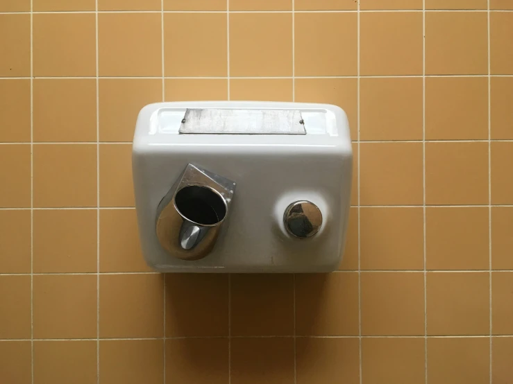 a close up of a metal wall mounted soap dispenser