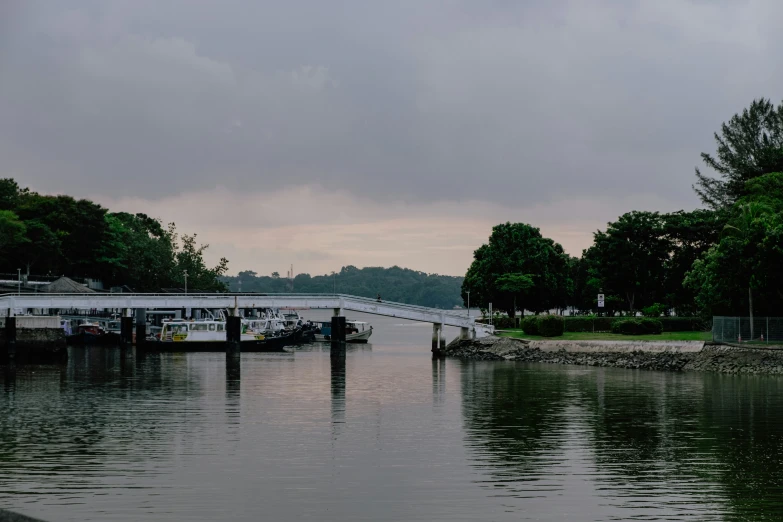 boats docked at the end of the river under a cloudy sky