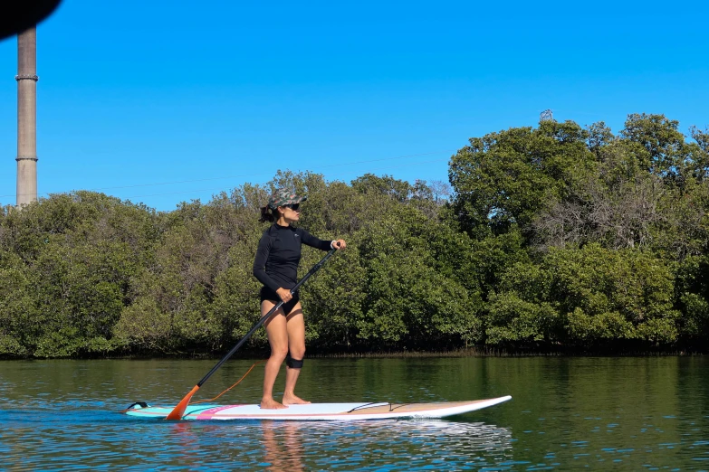 a man standing on a paddle board and paddling in the water