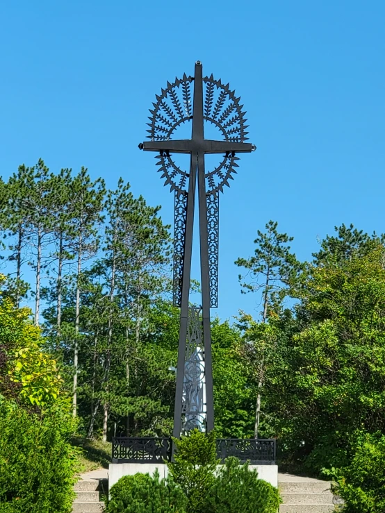 this statue is sitting in the grass and has a cross on top of it