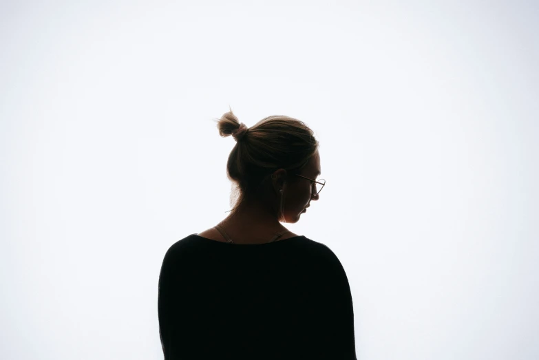 silhouette of woman in glasses against white sky