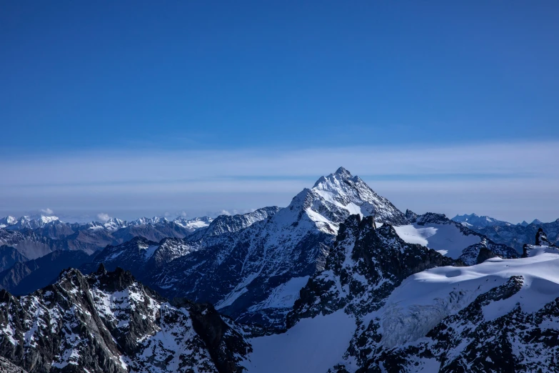 the snow - covered mountains and valleys near a blue sky