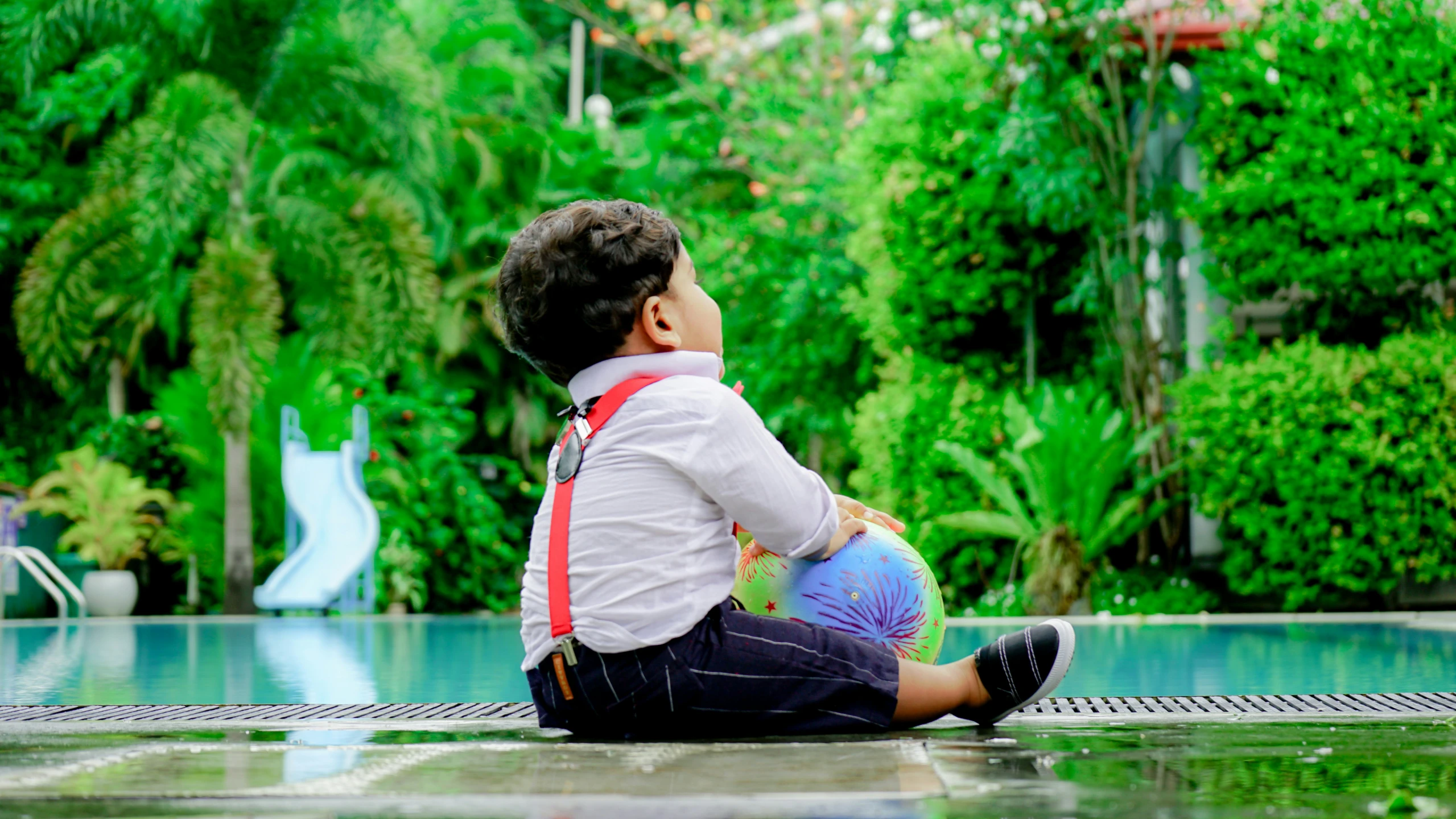 a child sitting on the ground in front of a pool