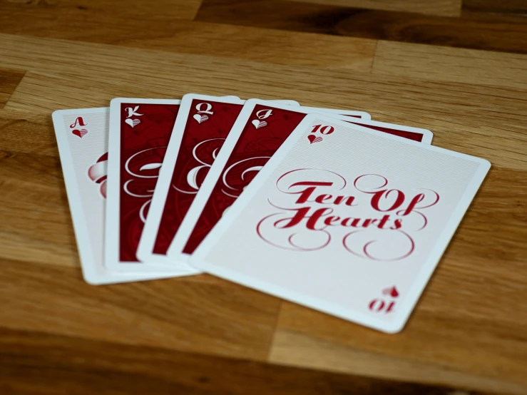 five playing cards on top of a wooden table