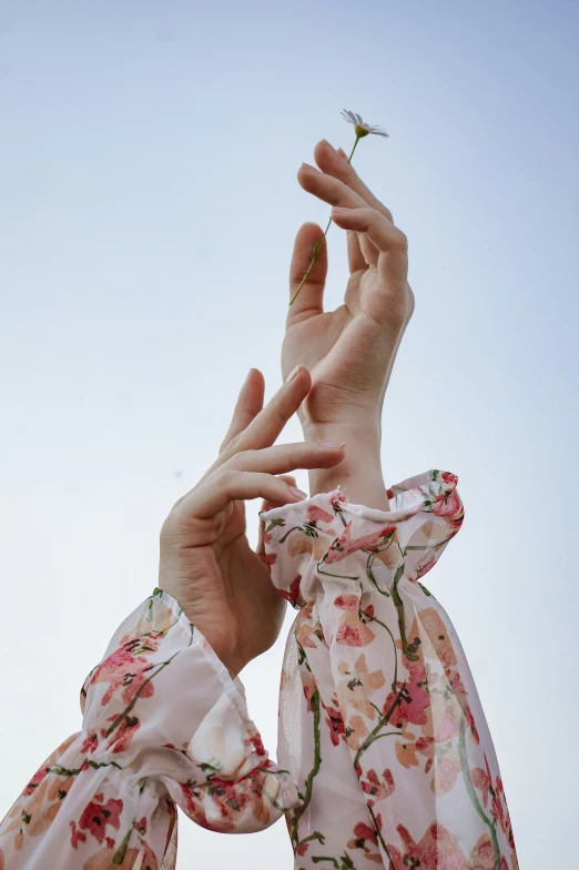 two women with hands holding a small flower