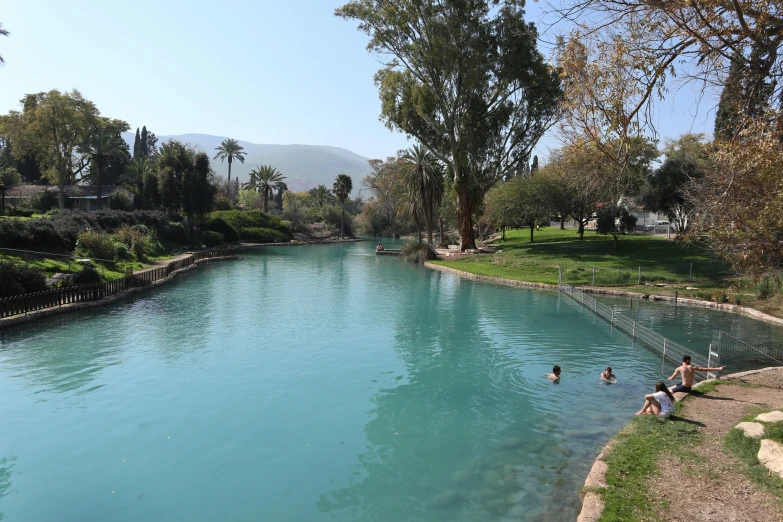 the people are swimming in the clear blue river