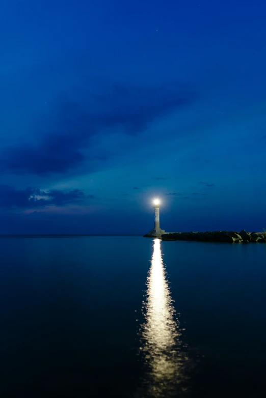 a full moon is rising behind the lighthouse