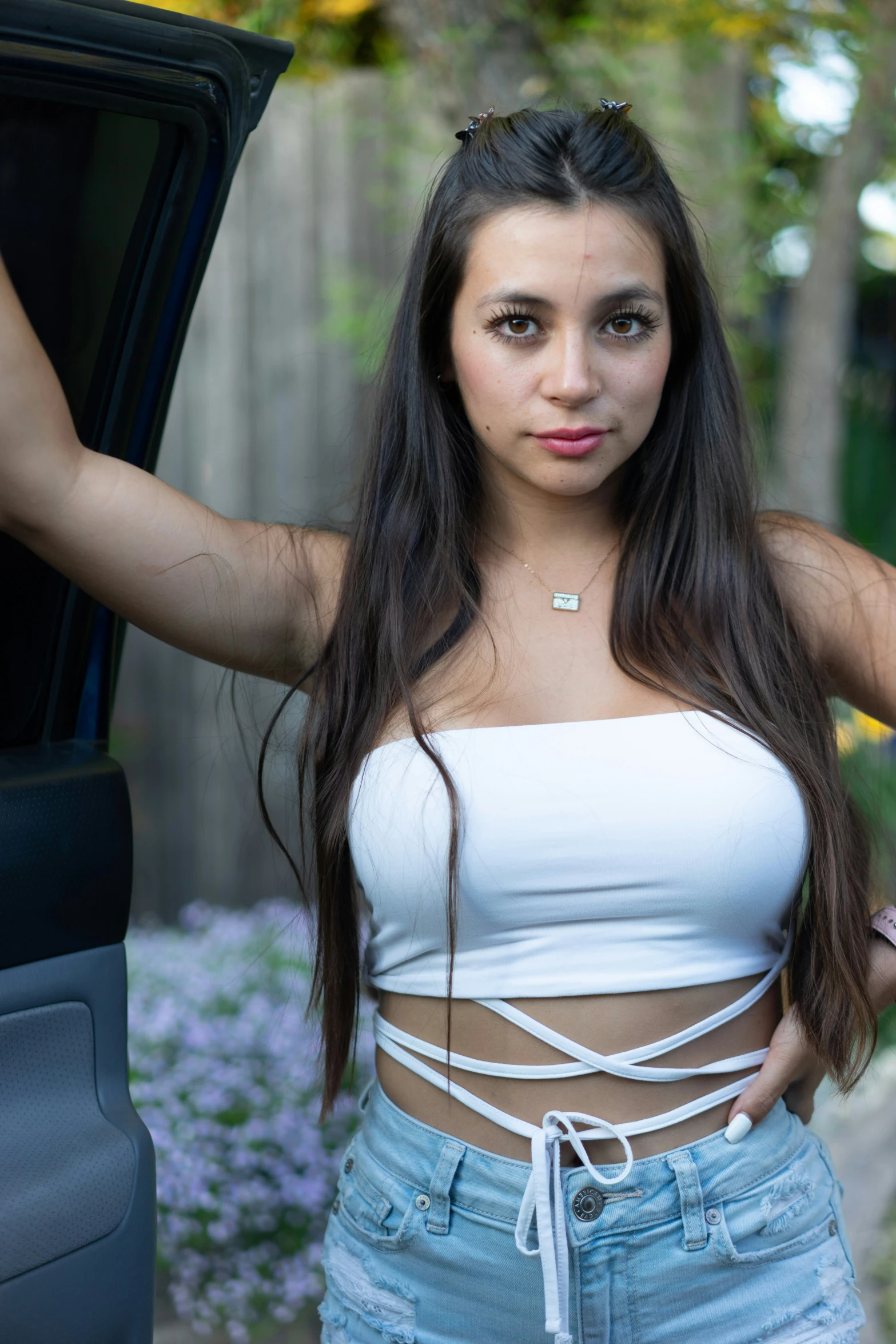 a young woman poses in front of her car