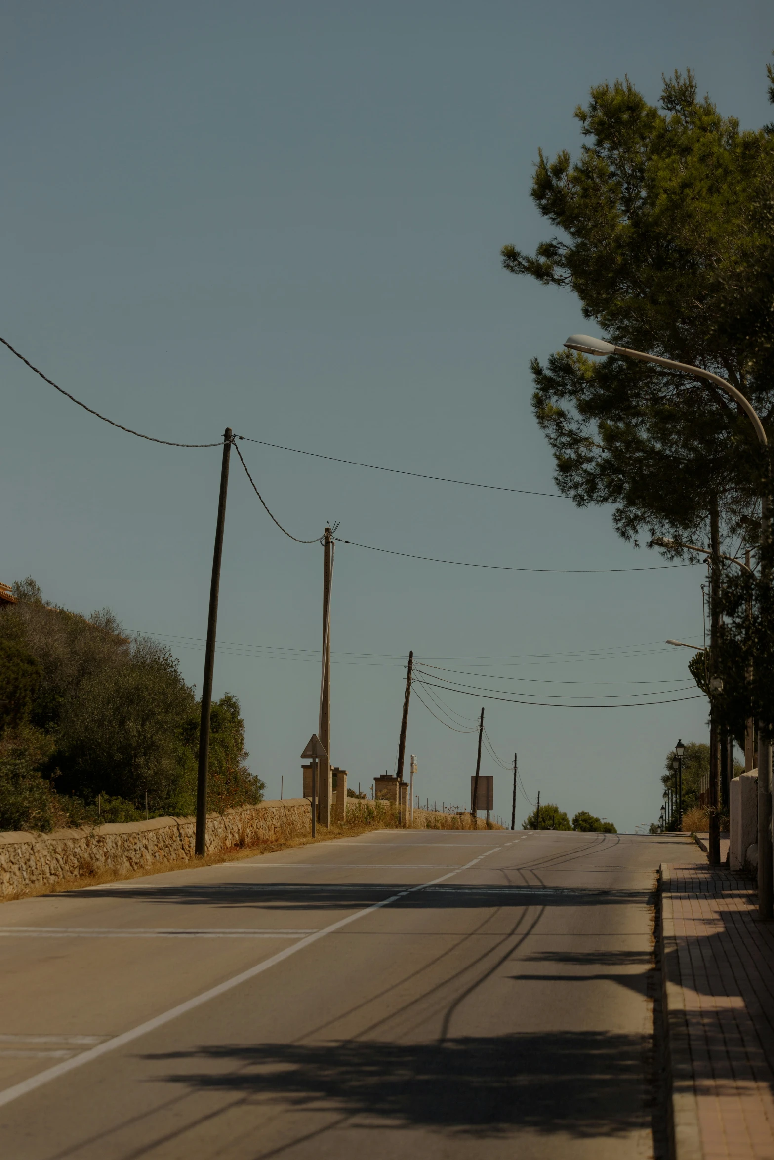 a view of an empty street with a stop light and wires