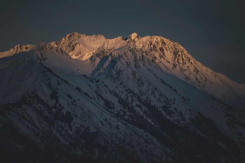 a large snow covered mountain peak with a moon