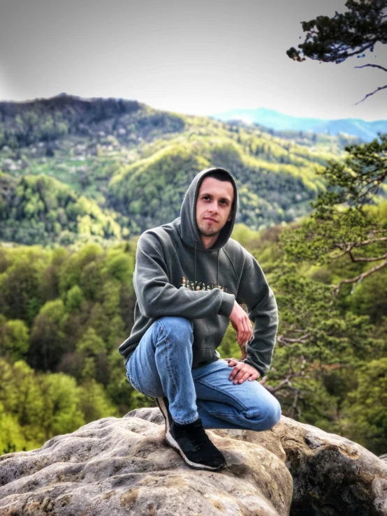 the young man is sitting on top of the rock