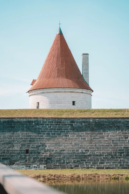 a stone wall surrounding a brick wall and a tall tower with two chimneys