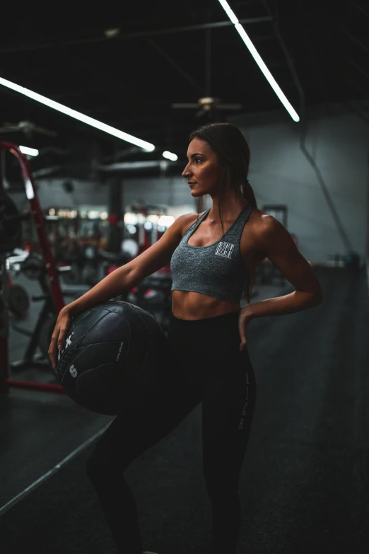 a woman carrying a basketball in a gym
