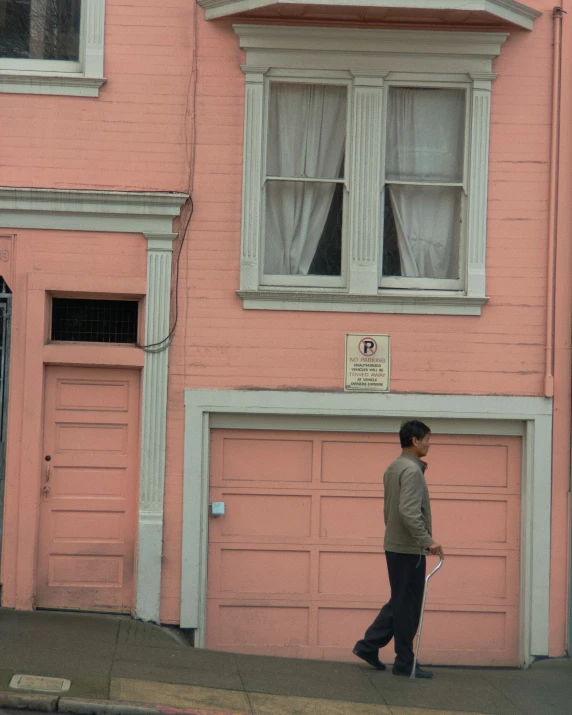 a person walking past a tall pink building