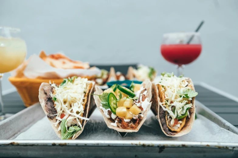 a silver tray topped with three tacos covered in toppings