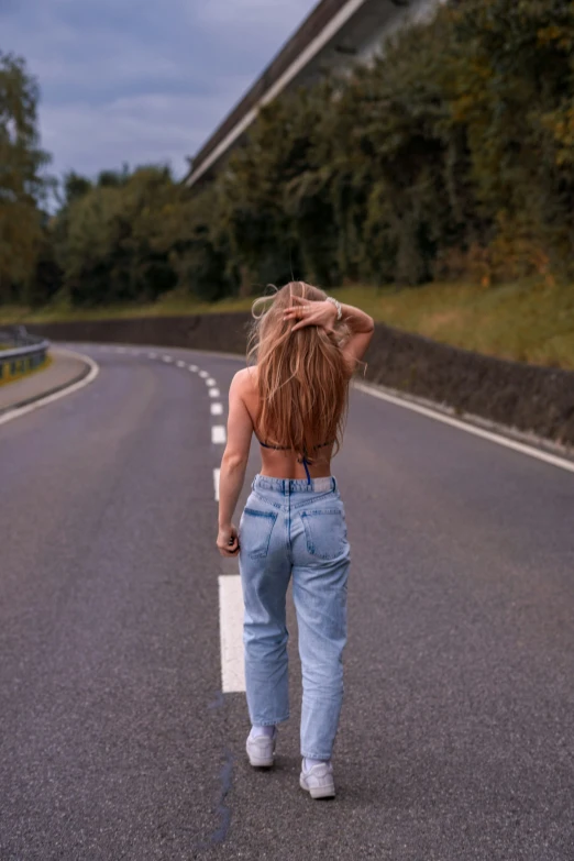 woman with long hair walking across a highway