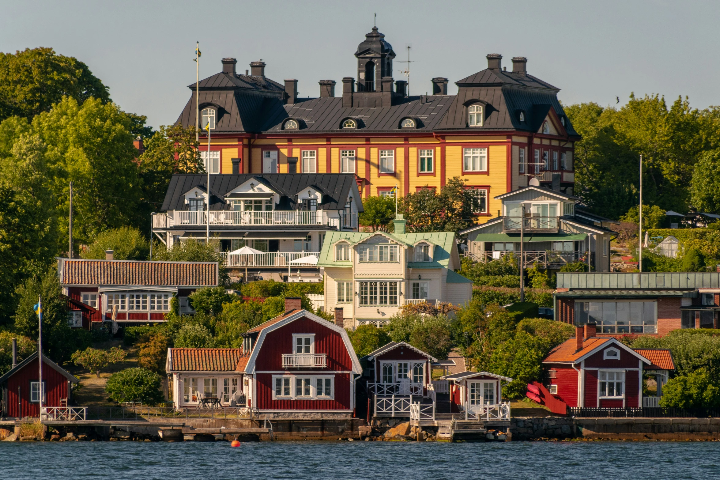 the view of a large brick building on the shore of a river