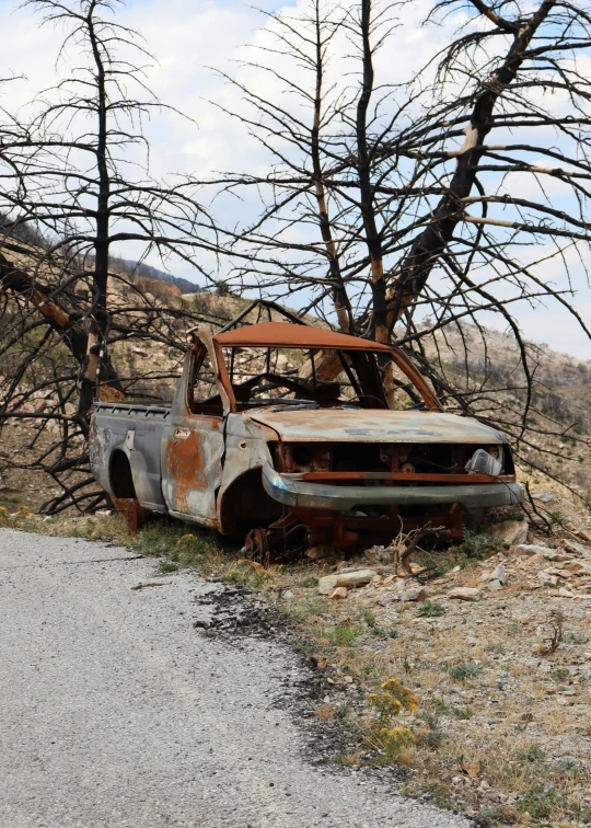 an old abandoned pick up truck sits on the side of the road