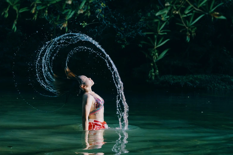 a woman splashes water from her head as she stands in a lake