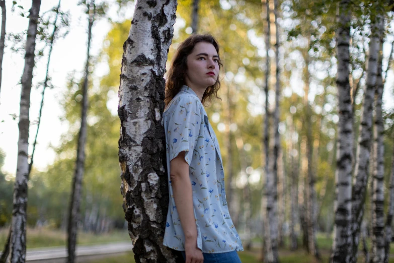 a young woman leaning on the side of a tree