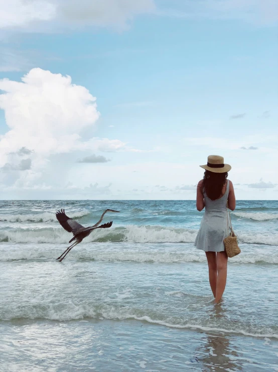 a woman walking on the beach in front of a crane