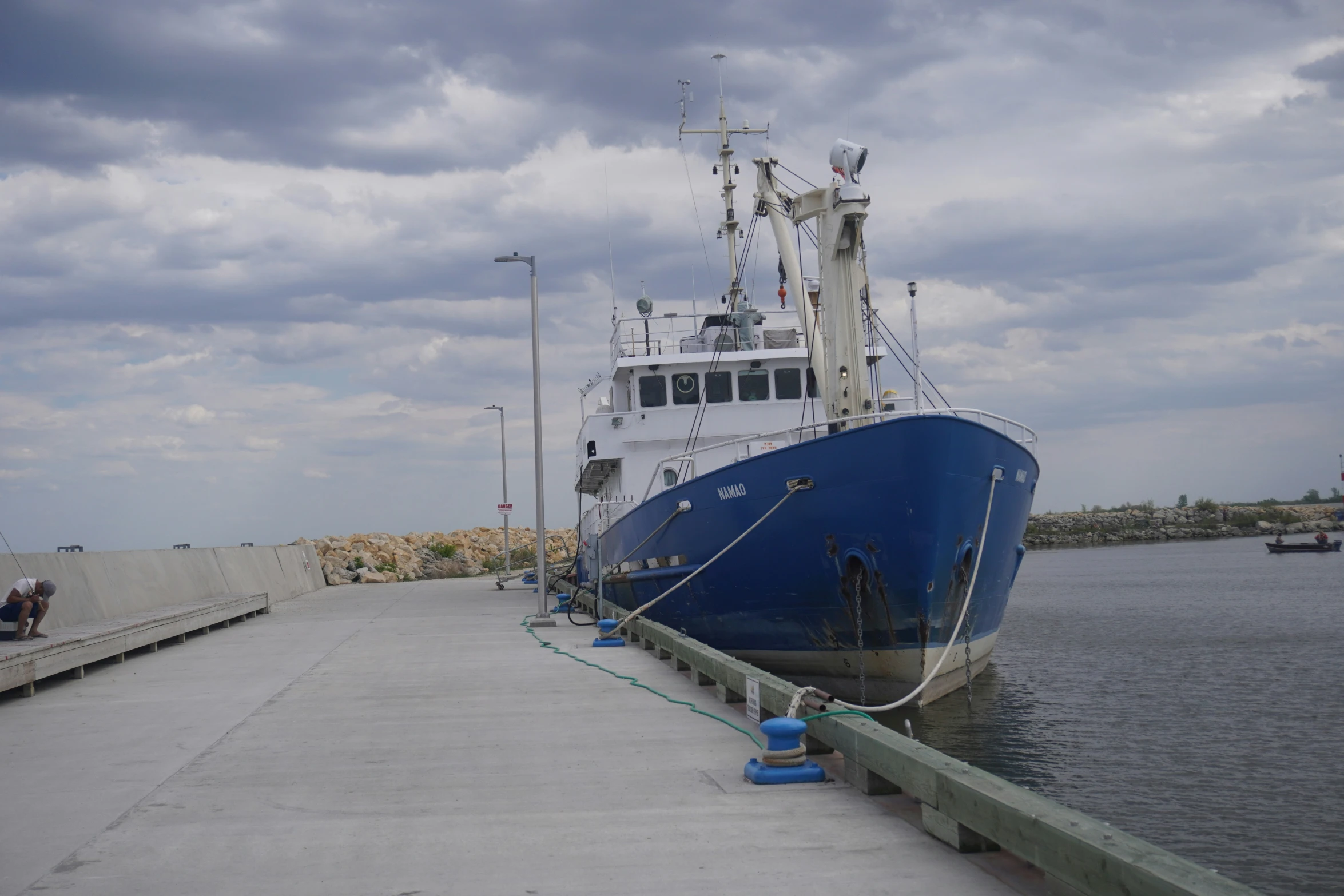 a blue boat sitting on top of a river next to a pier