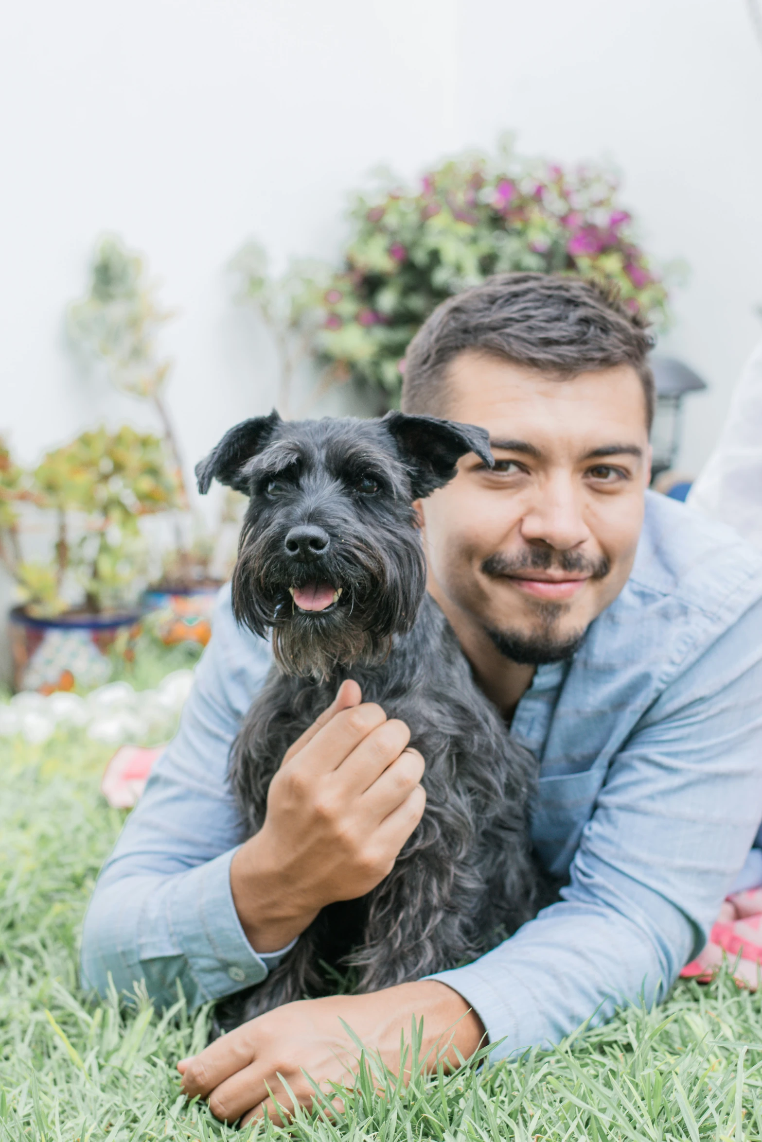 a young man sitting on the grass with his black dog