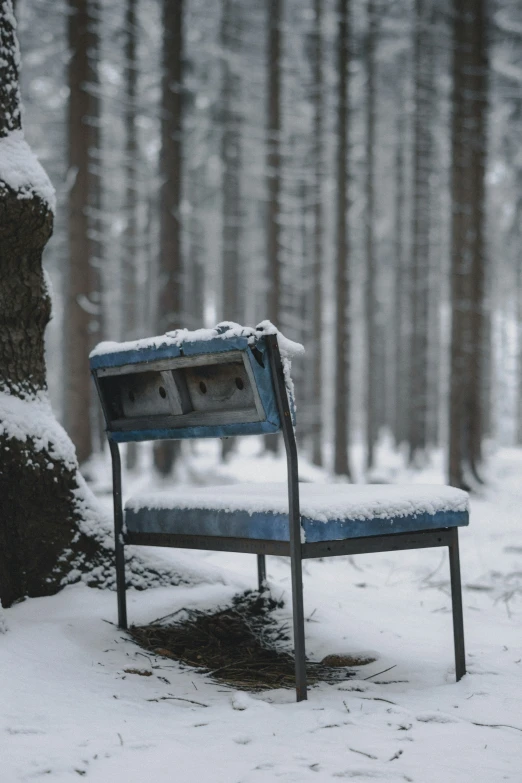 an empty blue chair is seen in the snow