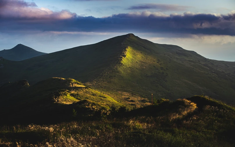 a big mountain that has some grass growing up it