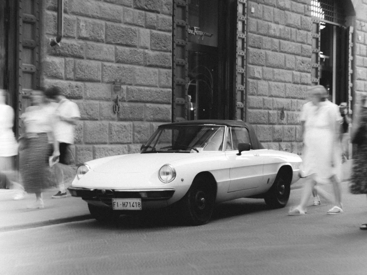 an old white car parked next to some people