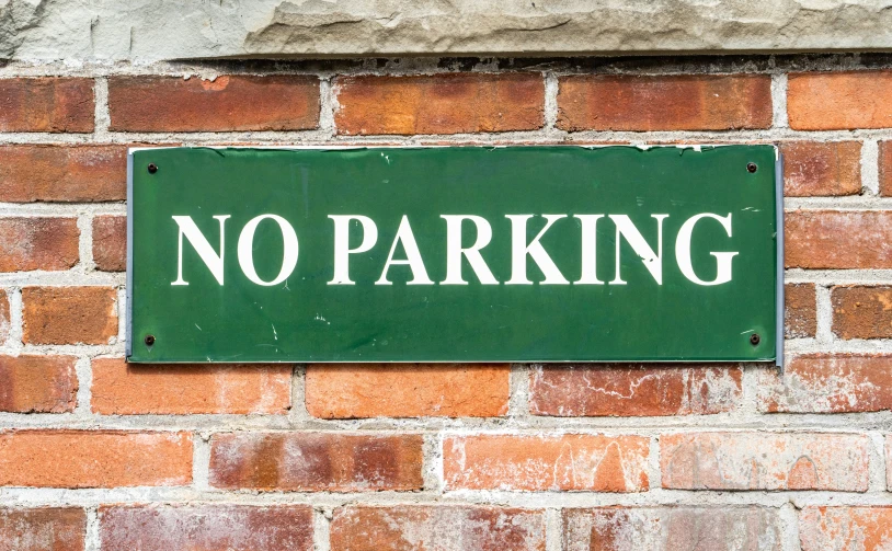 a green sign that is posted on the side of a brick wall