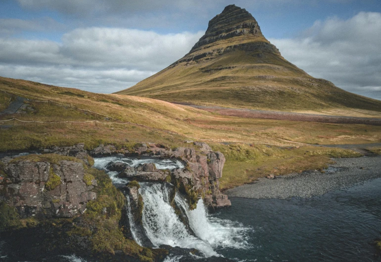 a mountain towering over the top of a small river