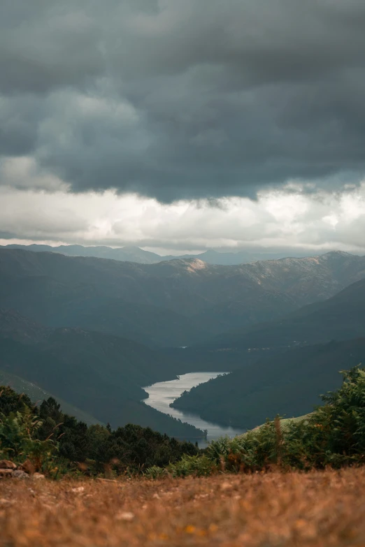 a cloudy landscape over a lake and mountains