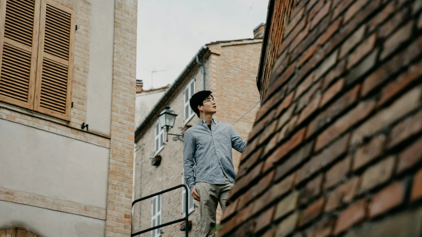 a man on a cell phone standing in the alley of an old brick building