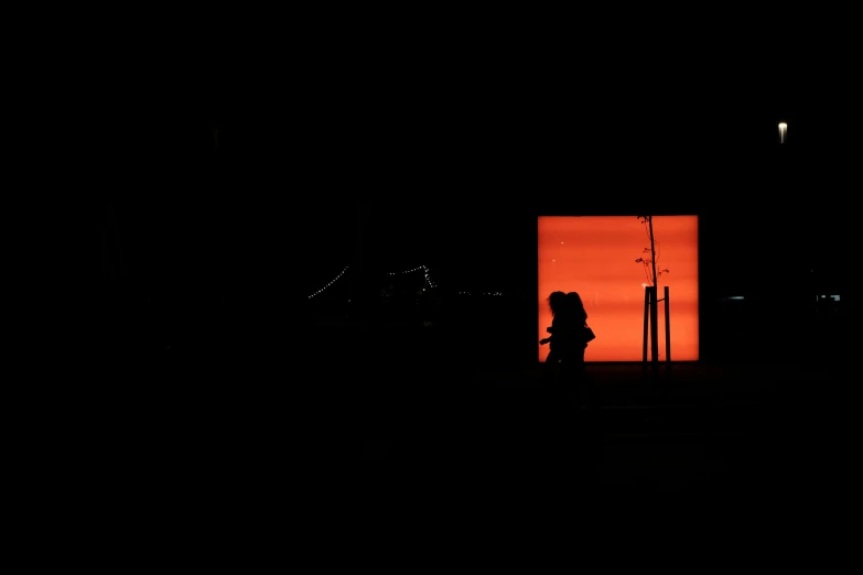 the silhouette of a person stands in front of an orange background