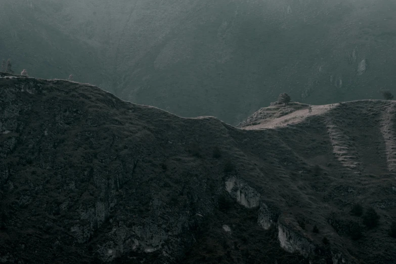 a group of people walking up a hill with mountains in the background