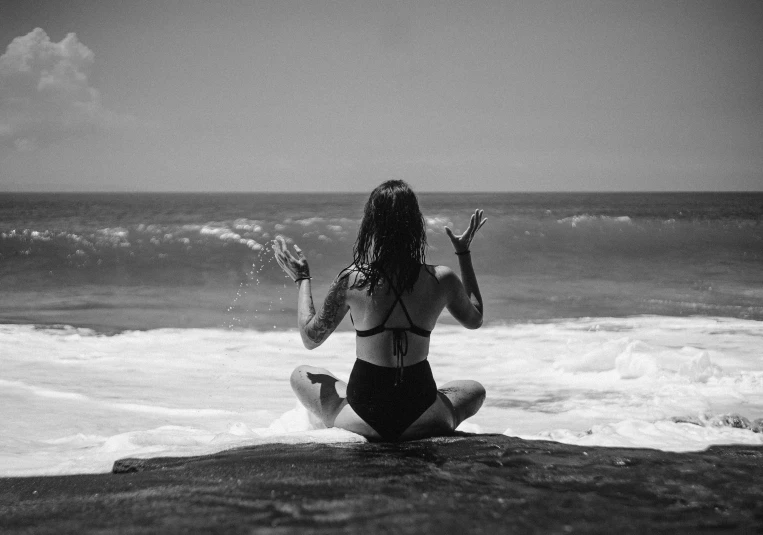 a woman is sitting on a rock and holding out her arms