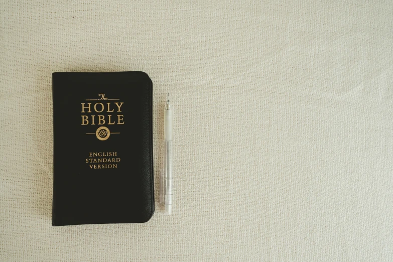 a bible on the ground next to a pen