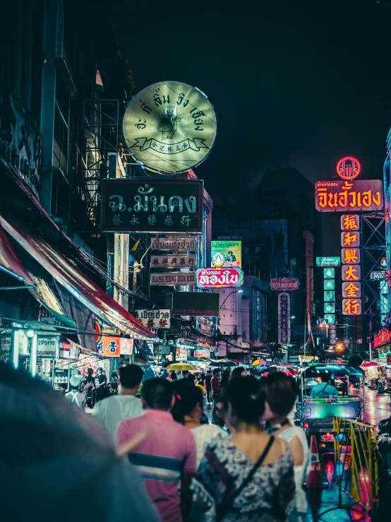 a night time scene with lots of signs and a clock in the background