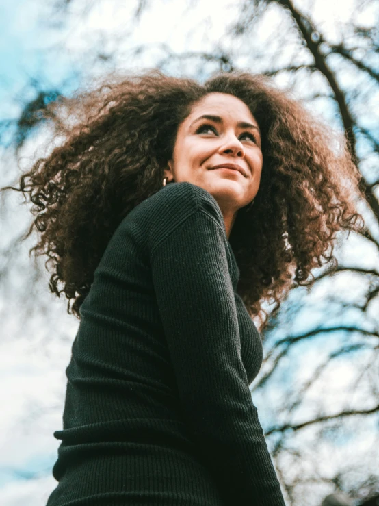 a woman with large hair and looking up at the sky