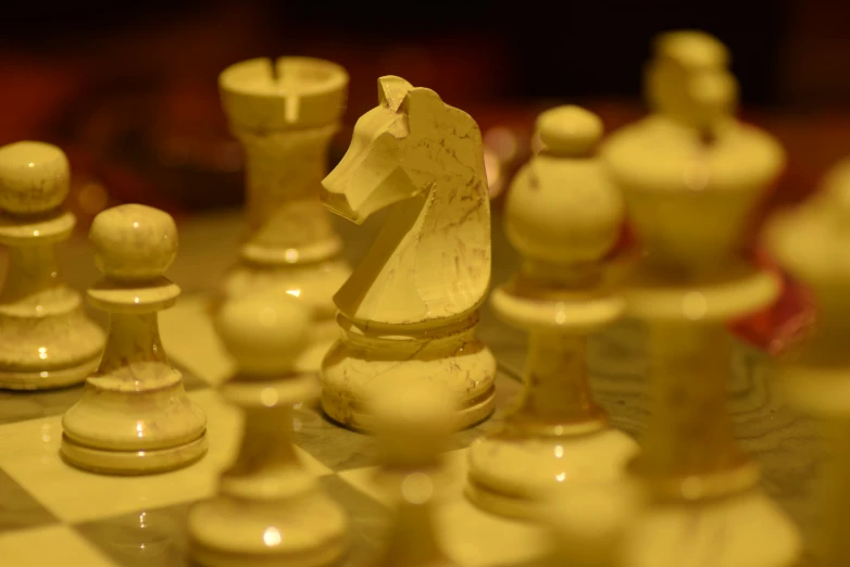 white and beige chess pieces sitting on a checkered tile