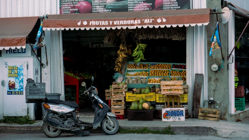a small motorcycle parked next to some fruit on display