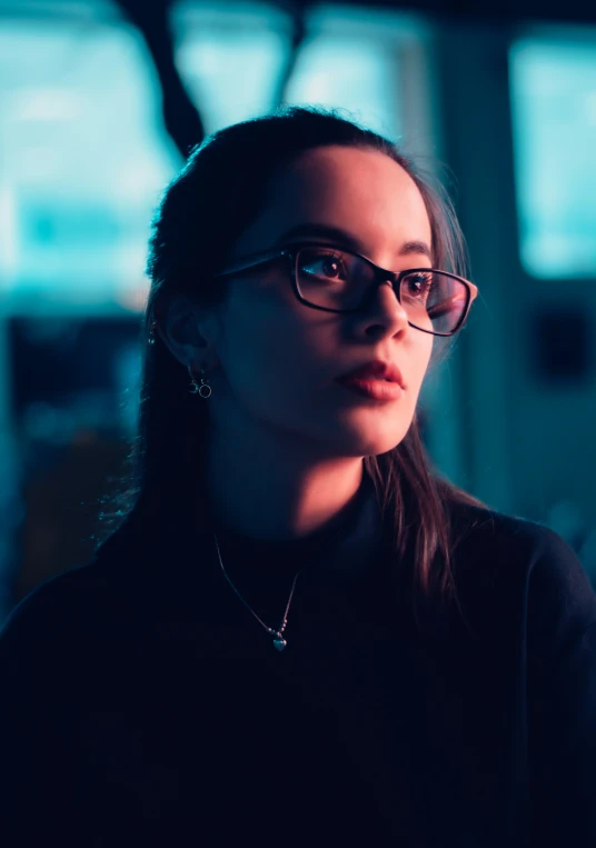 a woman wearing glasses is staring into the distance