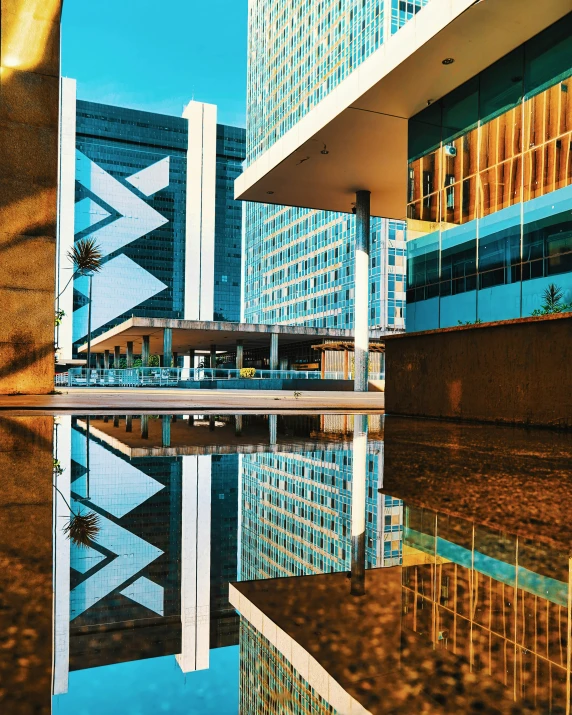 a reflection in a still pool of water next to a tall building