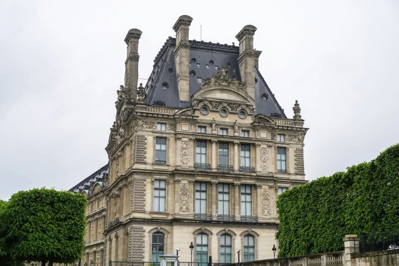 a stone building has many windows and bushes in front of it