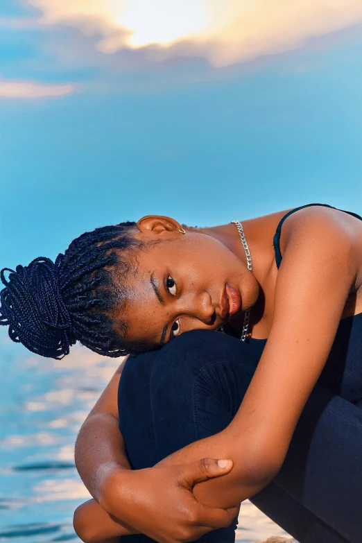 a woman sits on rocks near the ocean