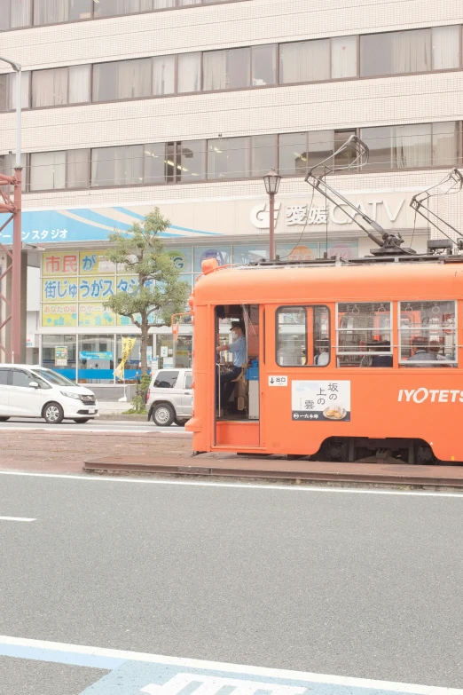 an orange trolley car sits on a city street