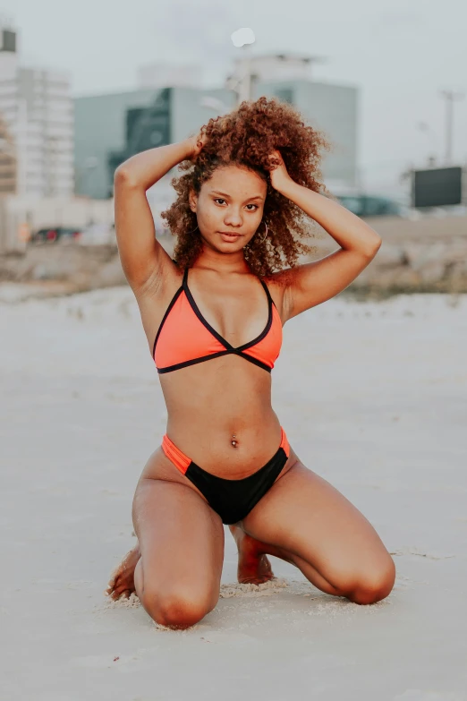 a woman posing in the sand wearing a bathing suit